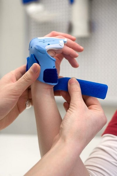 Nahaufnahme von Haenden einer Ergotherapeutin die einem Patienten eine Schiene an der Hand anpasst in der Handtherapie des VAMED Rehazentrum Karlsruhe