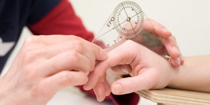 Nahaufnahme von Haenden einer Ergotherapeutin die Fingergelenke eines Patienten ausmisst in der Handtherapie im VAMED Rehazentrum Karlsruhe 