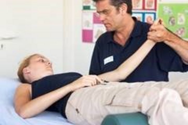 Eine auf dem Ruecken liegende Patientin bekommt eine PNF Behandlung in der Physiotherapie Abteilung des VAMED Rehazentrum Karlsruhe