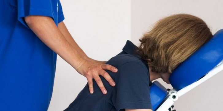Nahaufnahme einer Massage Behandlung am Arbeitsplatz in sitzender Position des Patienten