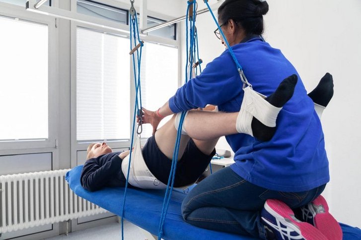 ein Patient wird von einer Physiotherapeutin im Schlingentisch behandelt in der Physiotherapie in Karlsruhe