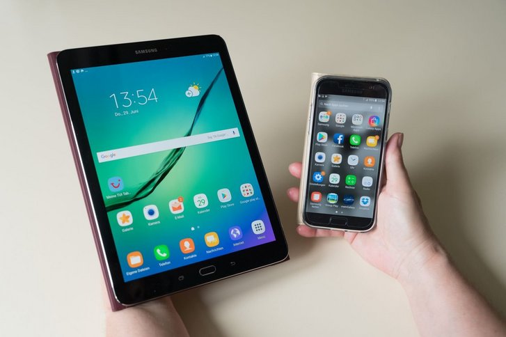 Haende halten Tablet und Smartphone